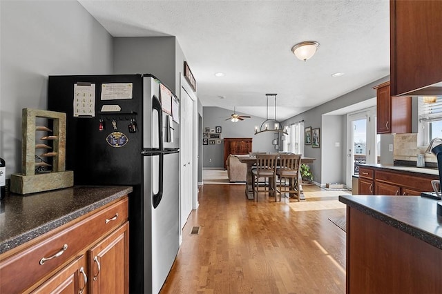 kitchen featuring light wood-style flooring, dark countertops, backsplash, and freestanding refrigerator