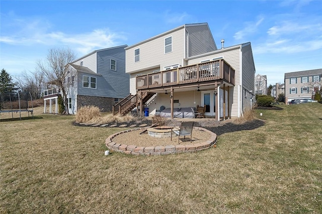 rear view of house with a trampoline, a patio area, a fire pit, a wooden deck, and stairs