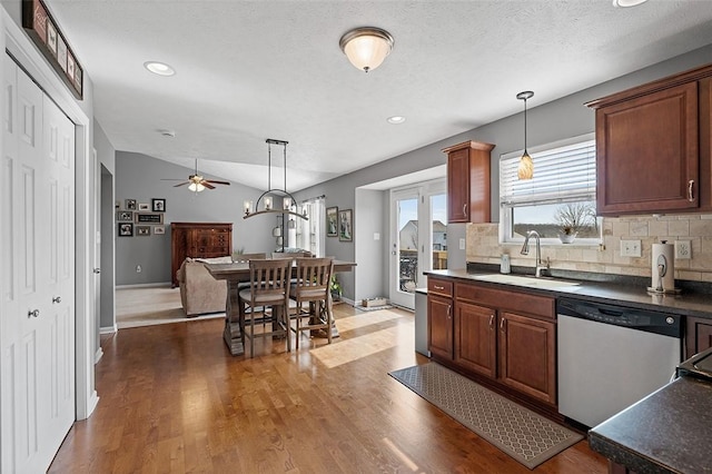 kitchen with dark countertops, pendant lighting, dishwasher, and a sink