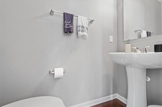 half bathroom featuring toilet, baseboards, and wood finished floors