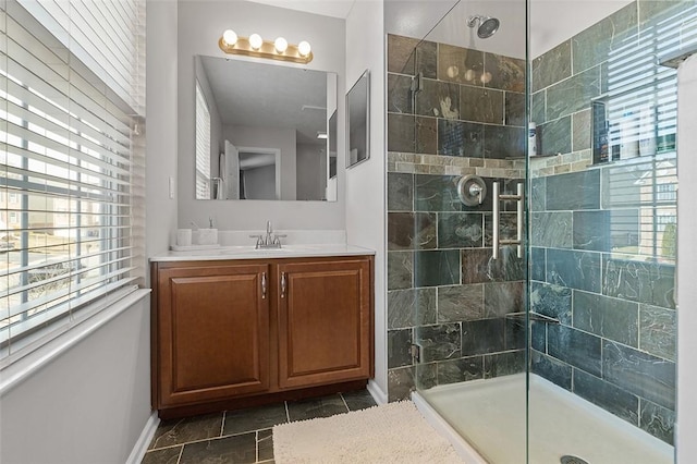 bathroom with a tile shower, vanity, and baseboards