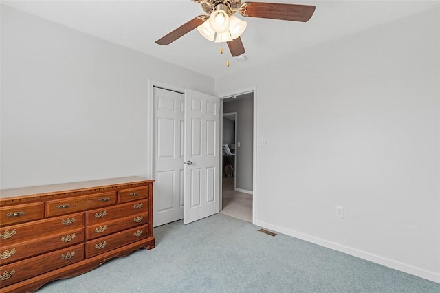 unfurnished bedroom featuring light carpet, ceiling fan, baseboards, and a closet