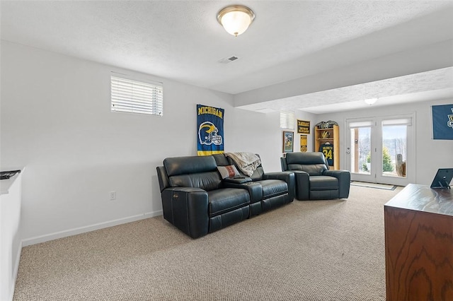 living area featuring a textured ceiling, carpet, visible vents, and baseboards