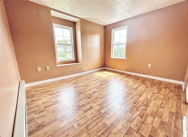 spare room featuring light wood-type flooring and baseboards