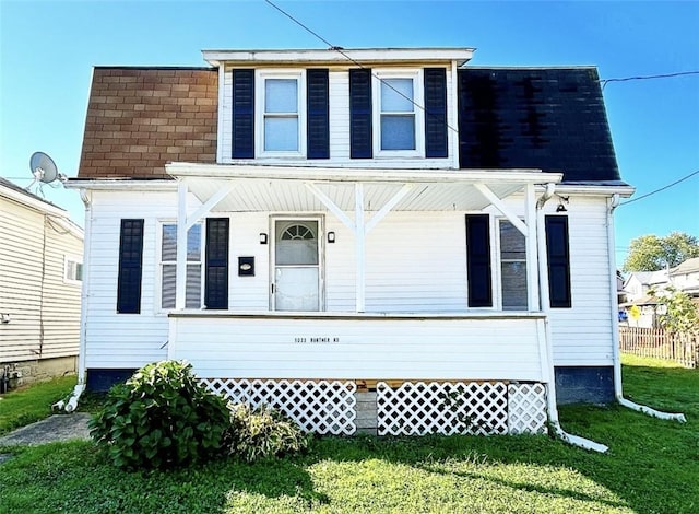 view of front of property with a front lawn, roof with shingles, a porch, and fence