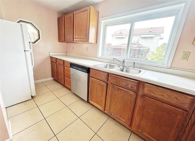 kitchen featuring freestanding refrigerator, brown cabinets, a sink, and stainless steel dishwasher