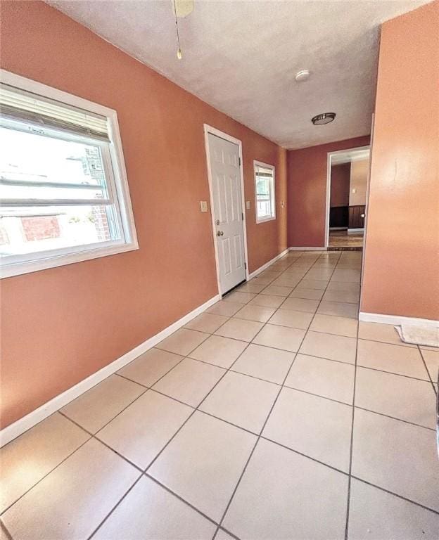 spare room with light tile patterned floors, baseboards, and a textured ceiling