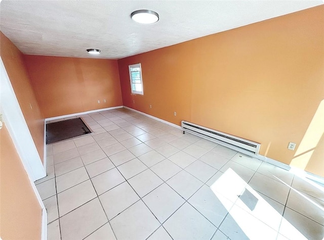 spare room with baseboards, a baseboard heating unit, a textured ceiling, and light tile patterned flooring