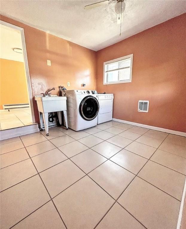 laundry room with light tile patterned floors, laundry area, baseboard heating, and washer and dryer