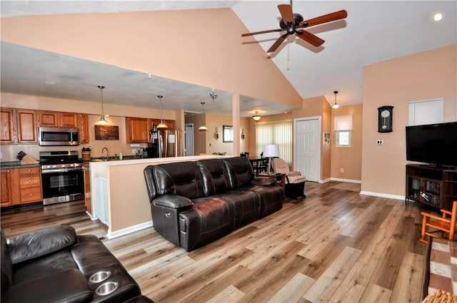 living room with ceiling fan, high vaulted ceiling, light wood-style flooring, and baseboards