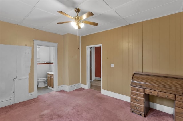 unfurnished bedroom featuring carpet, baseboards, ceiling fan, and ensuite bathroom