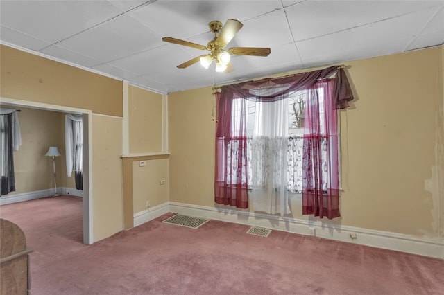 carpeted spare room with baseboards, visible vents, and a ceiling fan