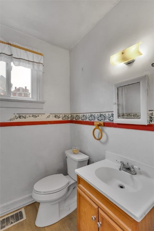 bathroom with toilet, wainscoting, visible vents, and vanity