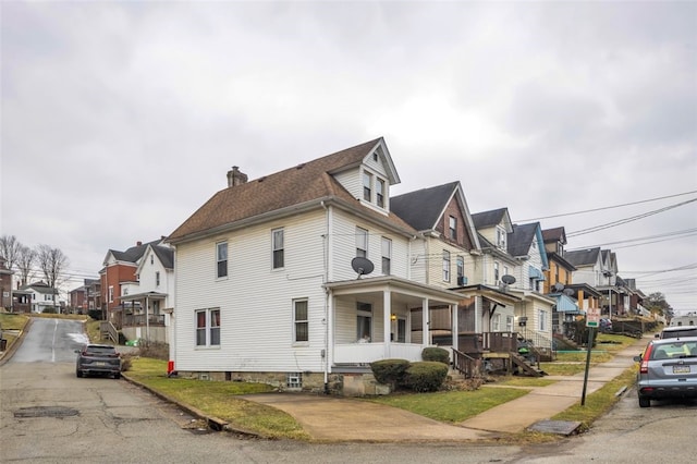 view of property exterior featuring a residential view, covered porch, and a chimney