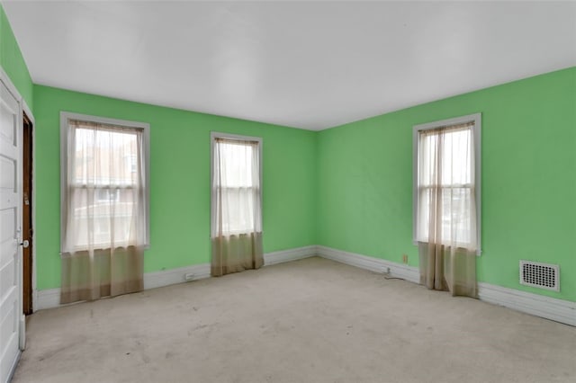 carpeted spare room featuring visible vents and baseboards