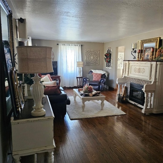 living area featuring a textured ceiling, wood-type flooring, and a glass covered fireplace