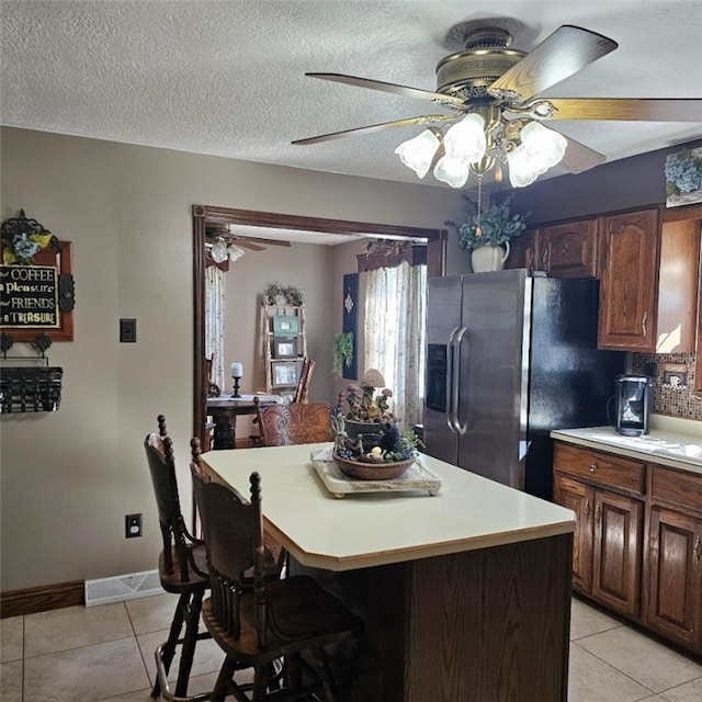 kitchen with light countertops, visible vents, stainless steel refrigerator with ice dispenser, and light tile patterned floors