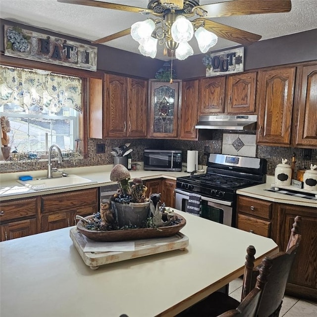 kitchen featuring light countertops, appliances with stainless steel finishes, a sink, and under cabinet range hood