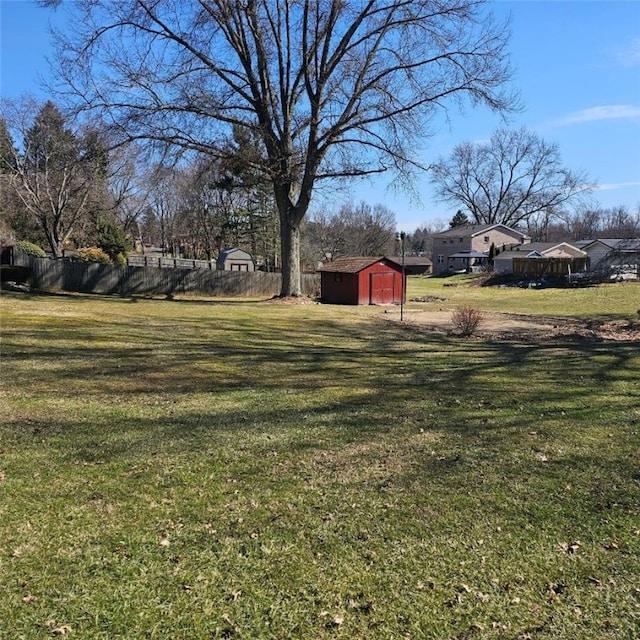 view of yard featuring an outdoor structure, fence, and a storage shed