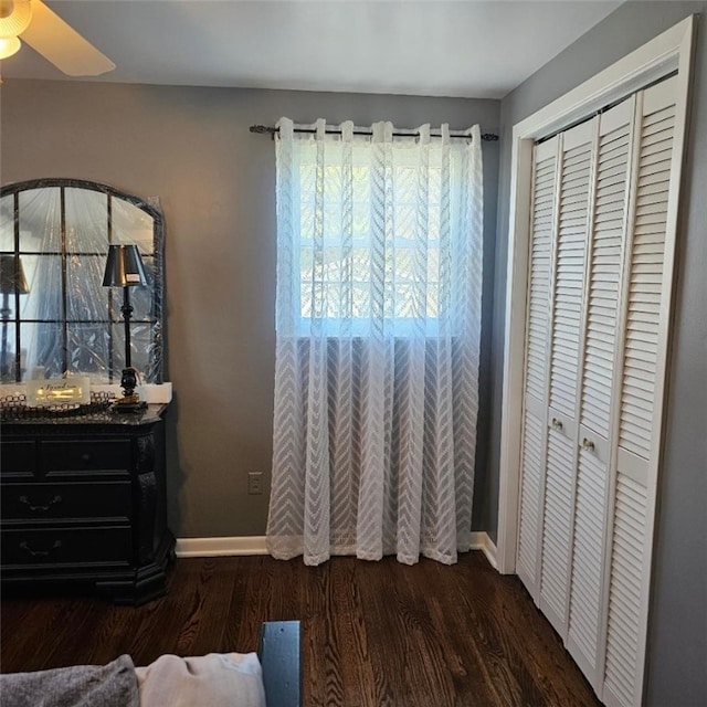 bedroom with baseboards, dark wood finished floors, and a closet