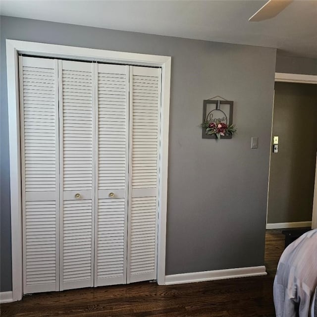 bedroom featuring baseboards, dark wood-style flooring, and a closet