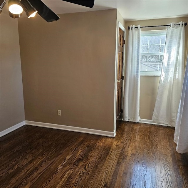 empty room featuring dark wood-style floors, ceiling fan, and baseboards