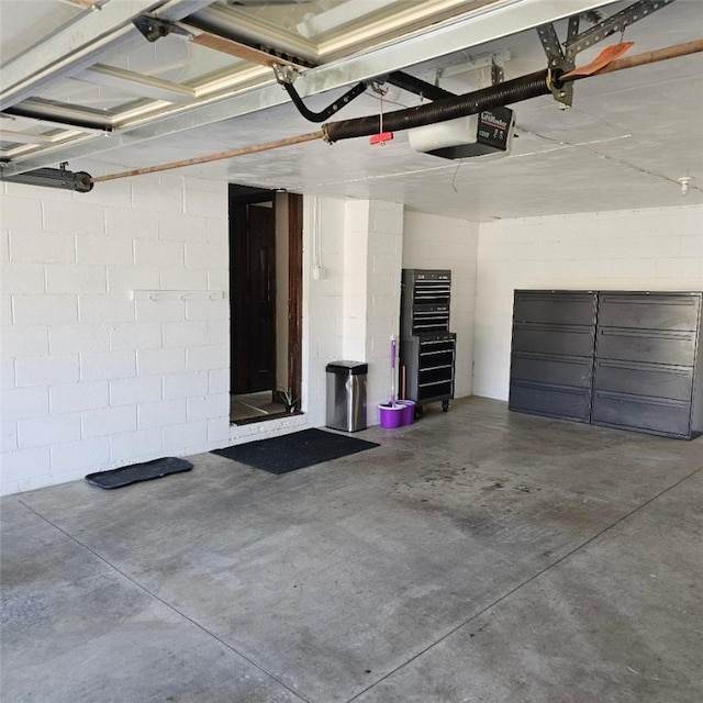 garage featuring a garage door opener and concrete block wall