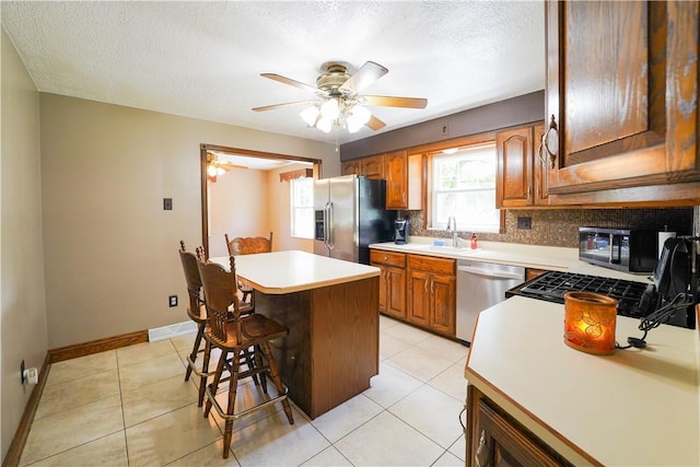 127 Stickle Rd, Chippewa Twp, PA 15010 - kitchen with stainless steel appliances, a kitchen island, a breakfast bar area, light countertops, and a ceiling fan