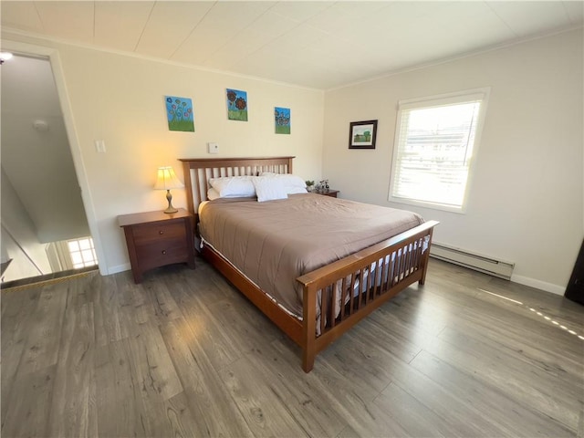 bedroom featuring ornamental molding, baseboards, baseboard heating, and wood finished floors