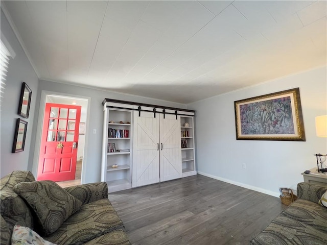 living room with dark wood-style floors, a barn door, crown molding, and baseboards