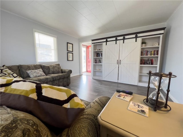 living area featuring ornamental molding, a barn door, wood finished floors, and baseboards