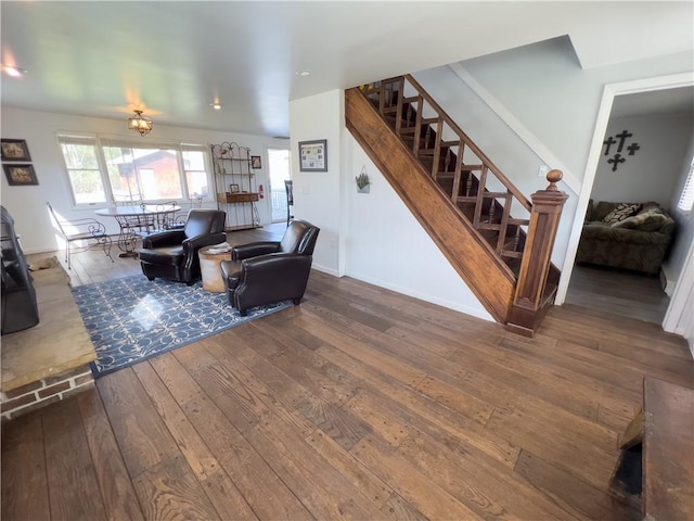 living room featuring wood-type flooring, baseboards, and stairs