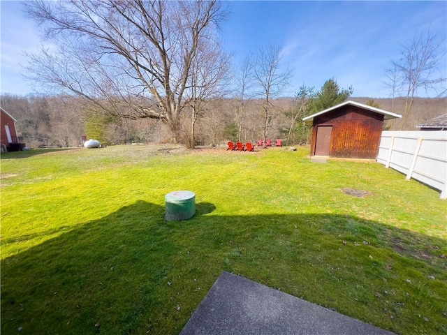 view of yard featuring an outbuilding, a shed, and fence