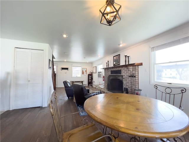 dining room featuring ornamental molding, a fireplace, wood finished floors, and baseboards