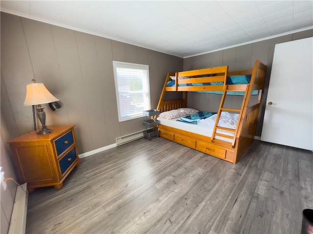 bedroom with a baseboard radiator, crown molding, baseboards, and wood finished floors