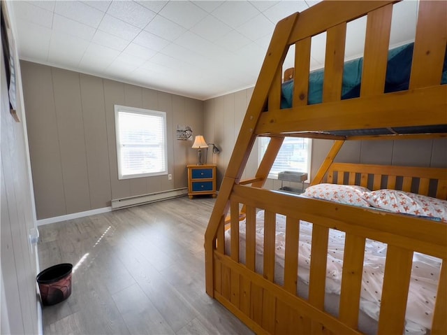 bedroom with a baseboard heating unit and wood finished floors