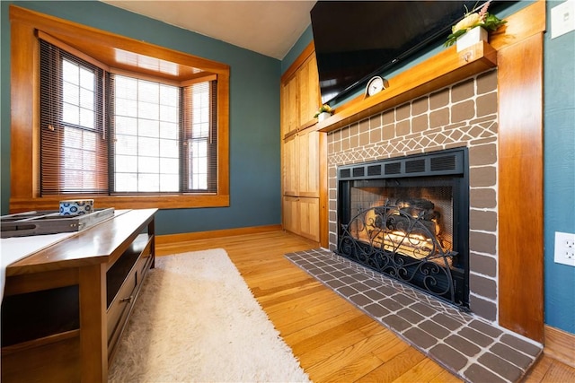 interior space featuring light wood finished floors, baseboards, and a tiled fireplace