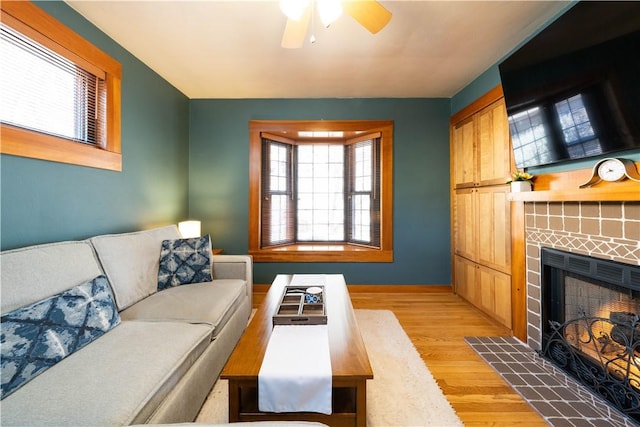 living area featuring a fireplace, wood finished floors, a ceiling fan, and baseboards