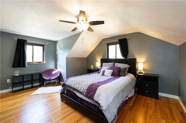 bedroom featuring multiple windows, vaulted ceiling, baseboards, and wood finished floors