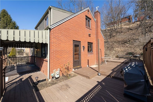 exterior space featuring a deck, brick siding, and a chimney