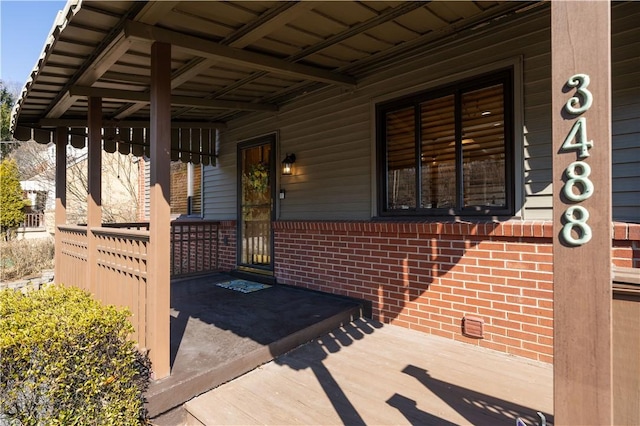 property entrance featuring covered porch and brick siding