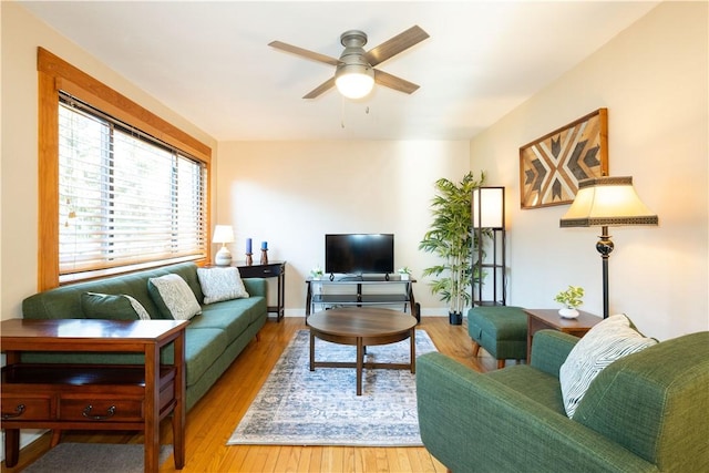 living room with ceiling fan, baseboards, and wood finished floors