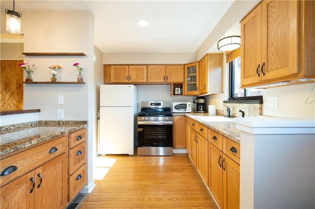 kitchen featuring light stone counters, white appliances, a sink, and open shelves