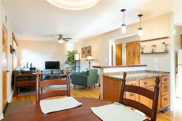 dining space with ceiling fan, light wood finished floors, and visible vents