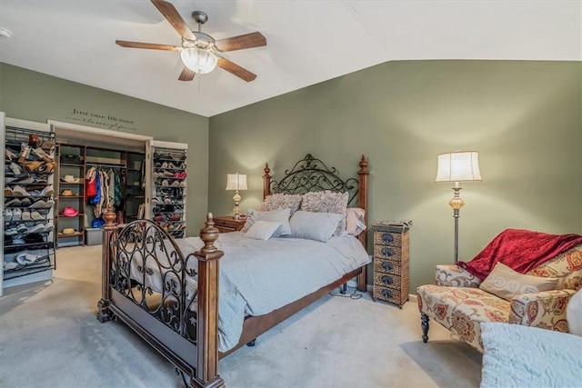 bedroom with lofted ceiling, a closet, carpet flooring, and a ceiling fan