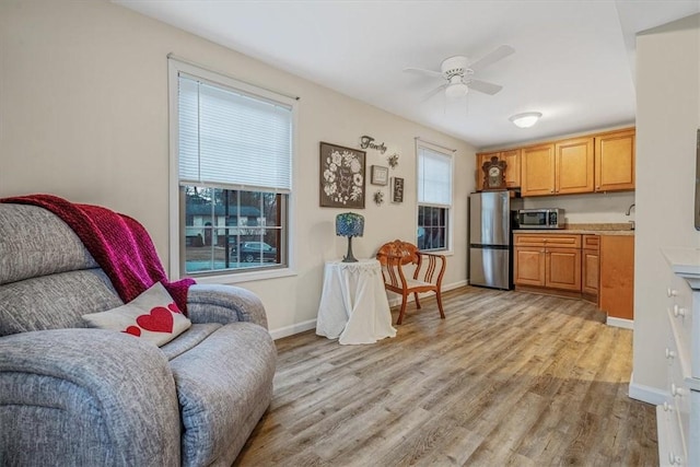 interior space with light wood-style flooring, baseboards, open floor plan, light countertops, and appliances with stainless steel finishes