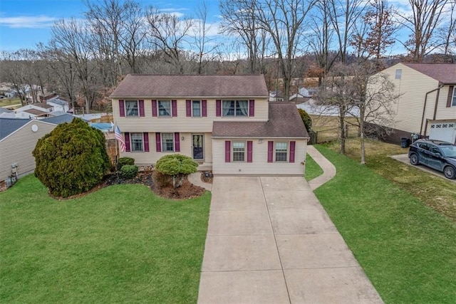 colonial house with roof with shingles, concrete driveway, and a front yard