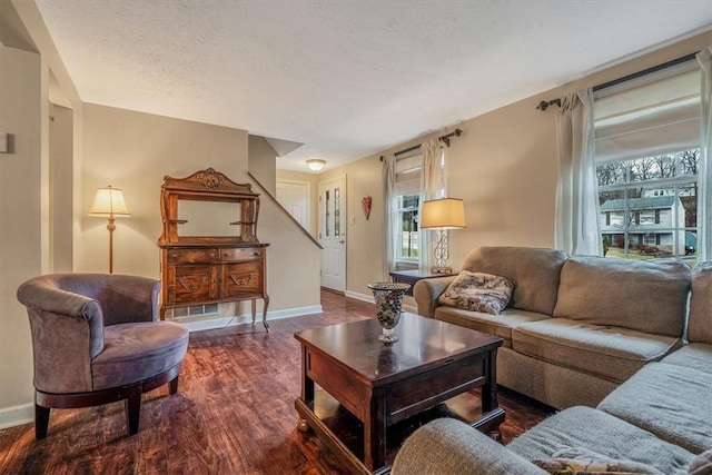 living area with a textured ceiling, baseboards, and wood finished floors