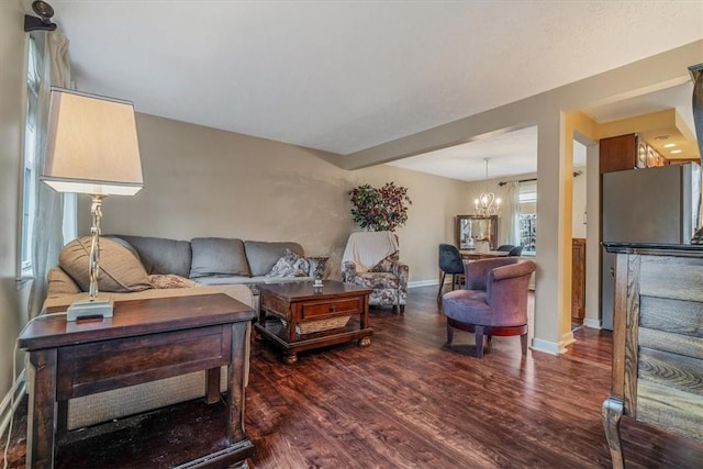 living area with baseboards, dark wood finished floors, and a notable chandelier