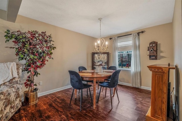 dining room with dark wood-style flooring, a notable chandelier, and baseboards